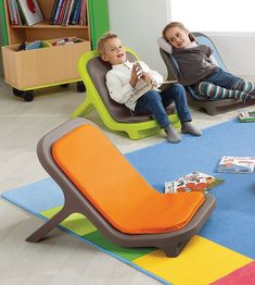 two children sitting on chairs in a room with colorful rugs and bookshelves