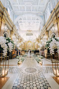 the aisle is decorated with white flowers and greenery for an elegant wedding ceremony at the palace