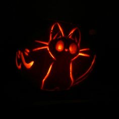 a pumpkin carved to look like a cat with glowing eyes and tail, in the dark