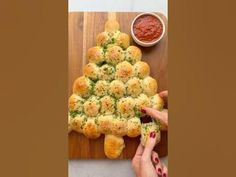 a christmas tree made out of rolls on a cutting board with dipping sauce in the background