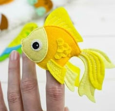 a hand holding a small yellow fish toy