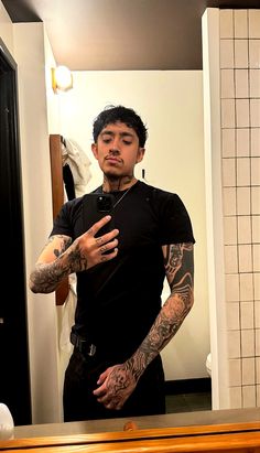 a man is standing in front of a mirror with tattoos on his arms and shoulder