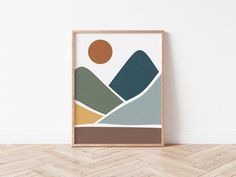 an art print with mountains in the background on a wooden floor next to a white wall