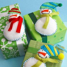 three snowmen are wrapped in green paper and sitting next to each other on presents