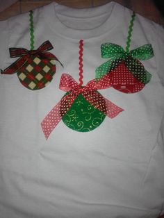 two christmas ornaments on a white shirt with red and green bows hanging from the front