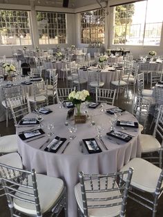 the tables are set with silver chairs and white tablecloths for an elegant wedding reception