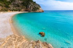 a beach with clear blue water and rocks