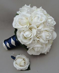 a bridal bouquet and boutonniere with white roses on the side, sitting next to each other