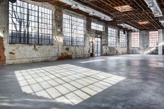 an empty warehouse with large windows and brick walls