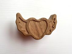 an elephant shaped wooden object on a white surface with the shape of a heart carved into it's trunk