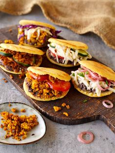 several sandwiches with meat and vegetables on a cutting board