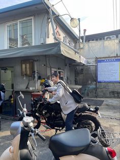 a man riding on the back of a motorcycle down a street next to a building