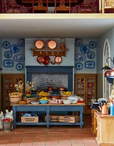 an old fashioned kitchen with pots and pans hanging from the ceiling, on display