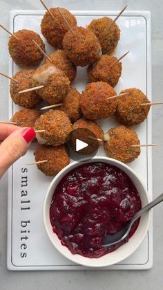 a plate with meatballs on skewers and cranberry sauce in a bowl