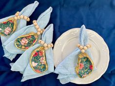 the napkins are decorated with flowers and gold accents on blue fabric, along with wooden bead necklaces