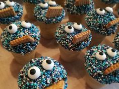 many blue cupcakes with white frosting and eyes on them are arranged in the shape of sesame street characters