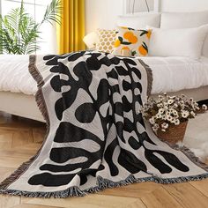 a white bed sitting next to a window covered in a black and white animal print blanket