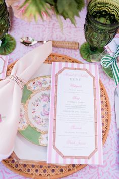 the table is set with pink and green plates, napkins, and place settings