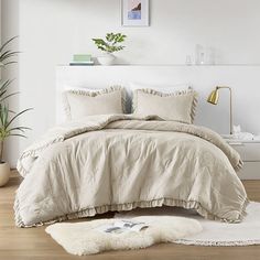 a bed with white sheets and pillows in a room next to a potted plant