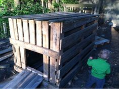 a little boy standing next to a wooden structure