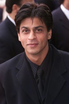 a man in a suit and tie posing for the camera with other people behind him