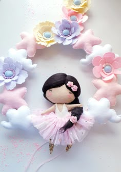 a doll is sitting in the middle of a wreath made out of felt flowers and fabric petals