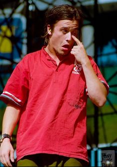 a man in red shirt holding his finger to his nose