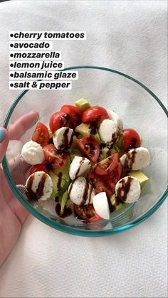 a person is holding a glass bowl with food in it that includes cherry tomatoes, avocado, mozzarella, lemon and tomato slices