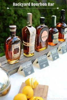 several bottles of bourbon sitting on top of a wooden table next to some lemons