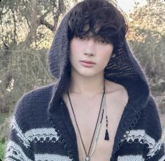 a young man wearing a hoodie with his shirt pulled up and necklaces hanging from his chest