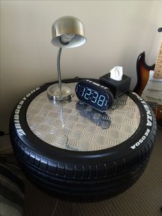 an alarm clock sitting on top of a table with a guitar in the back ground