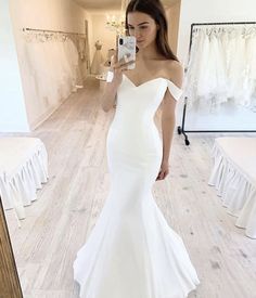 a woman in a white dress taking a selfie with her cell phone while standing in front of a mirror