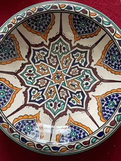 a bowl with an intricate design on the outside and inside, sitting on a red surface