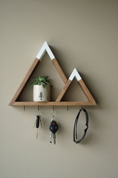 a wooden shelf with key hooks and keys hanging from it's sides next to a potted plant