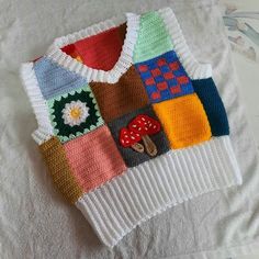 a knitted sweater with different colors and designs on the front is laying on a bed