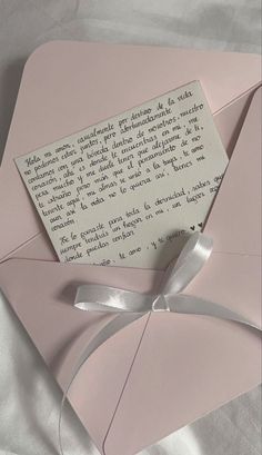 a piece of paper that is on top of a pink envelope with a silver ribbon