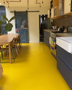 a kitchen with yellow flooring next to a dining room table and chairs in it