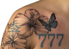 a close up of a tattoo with flowers and a butterfly on the back of a woman's shoulder