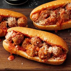 two meatball sub sandwiches on a wooden cutting board