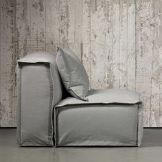 a grey couch with two pillows on it and a wooden wall in the back ground