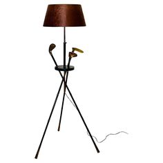 a lamp that is on top of a tripod with two golf clubs attached to it