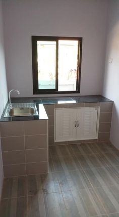 an empty kitchen with tile flooring and counter tops in front of a large window