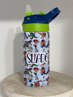 a blue and green sippy cup sitting on top of a wooden shelf