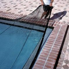 a man standing next to a swimming pool with a net on it's side