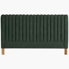 a green headboard with wooden legs and an upholstered design on the top