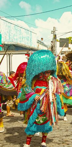 a group of people dressed in colorful costumes and headdress walking down a street