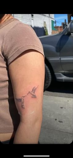 a woman with a bird tattoo on her left arm and right arm behind her back