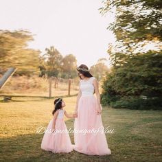 a mother and daughter in pink dresses holding hands