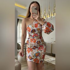 a woman taking a selfie with her cell phone in front of her, wearing a floral dress