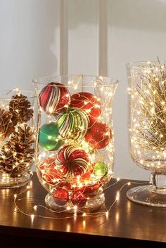 three glass vases filled with ornaments and lights